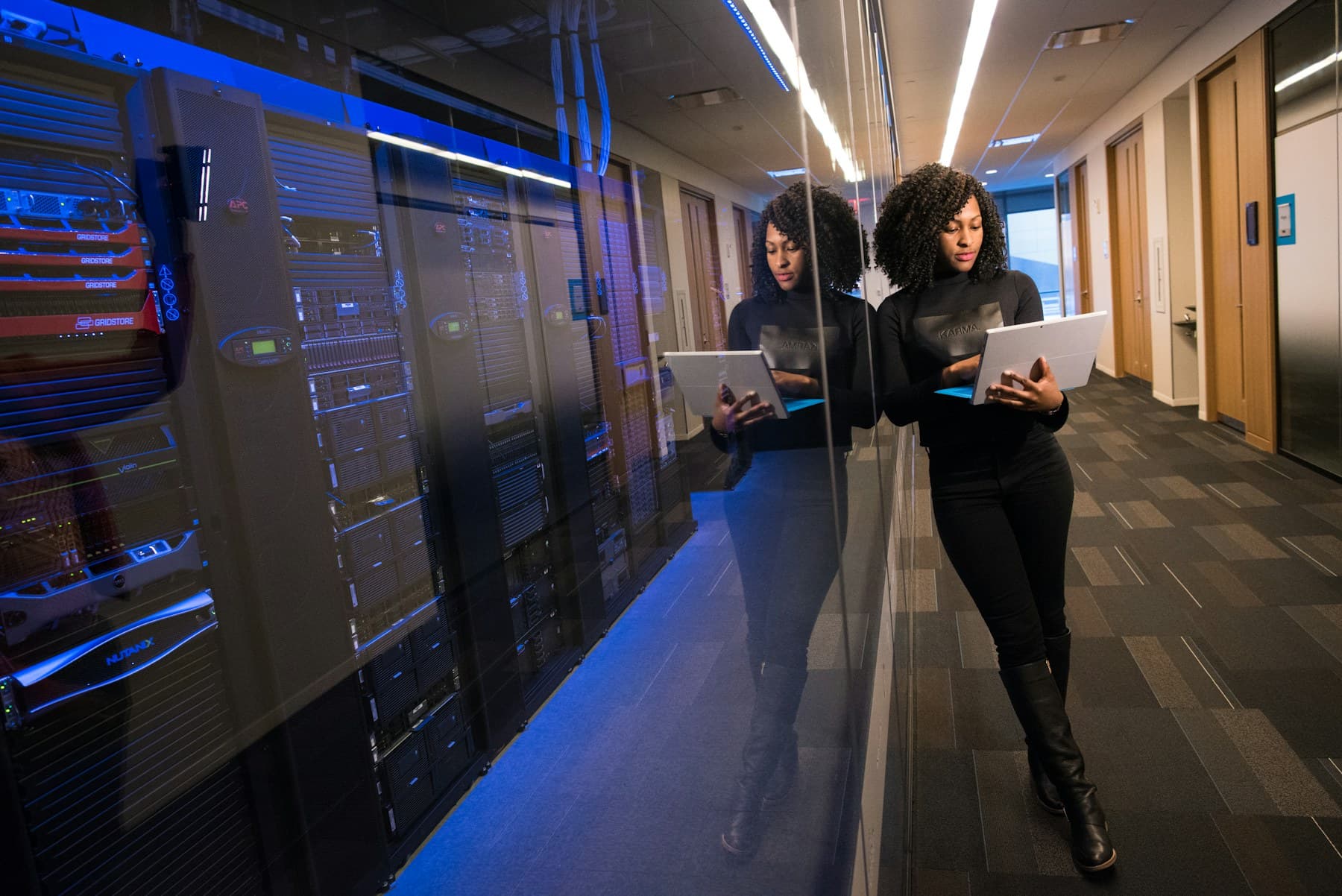 A security engineer reviewing infrastructure on a laptop beside a row of server racks